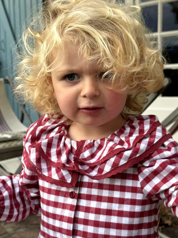 Detalle del vestido cálido para niña de vichy burdeos con doble cuello llevado por una niña pequeña