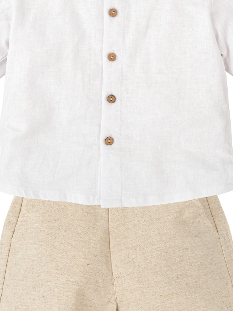 Detalle de la camisa blanca y el pantalón corto de lino y algodón liso beige para niño