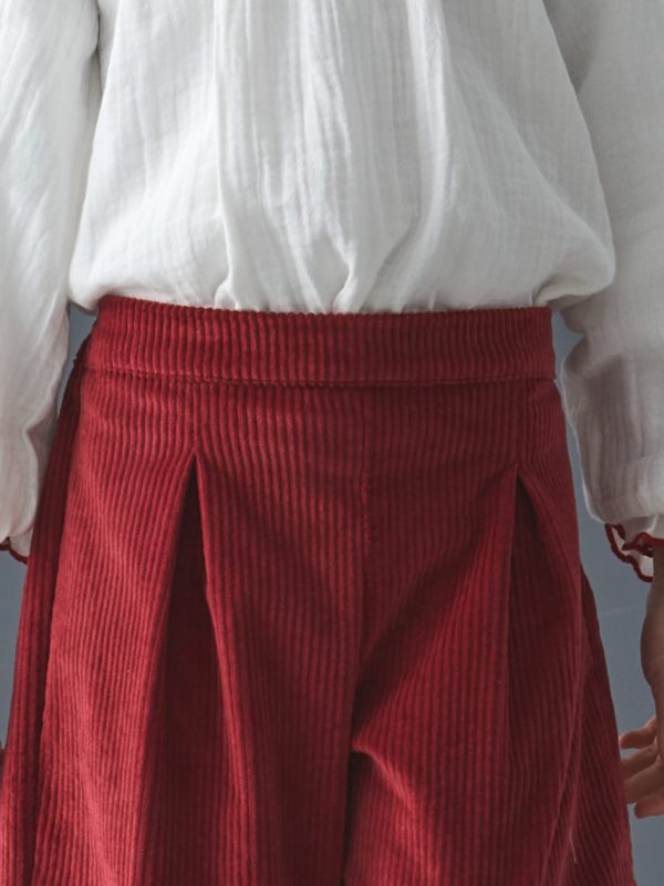 Détail du pantalon de l'ensemble fille blouse smockée et pantalon en velours côtelé rouge porté par une petite fille