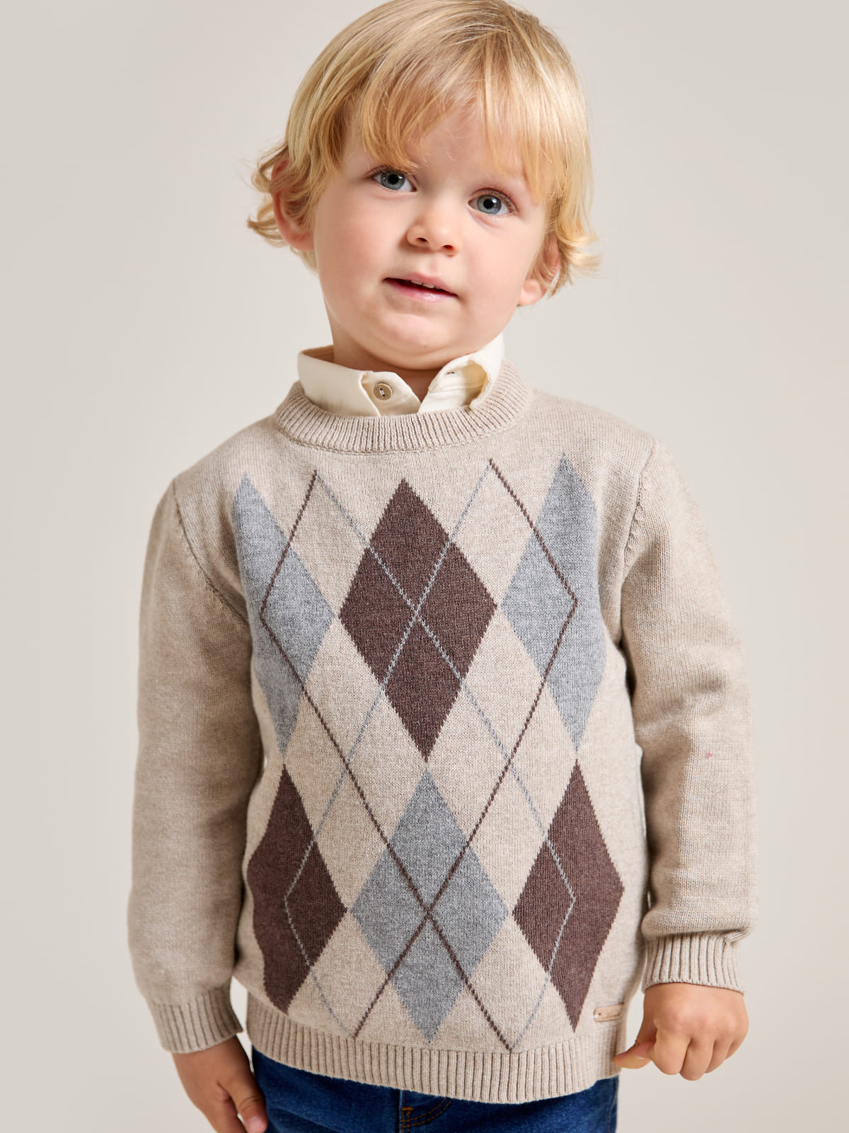 Pull garçon beige chiné en maille à motif de losanges porté par un garçon