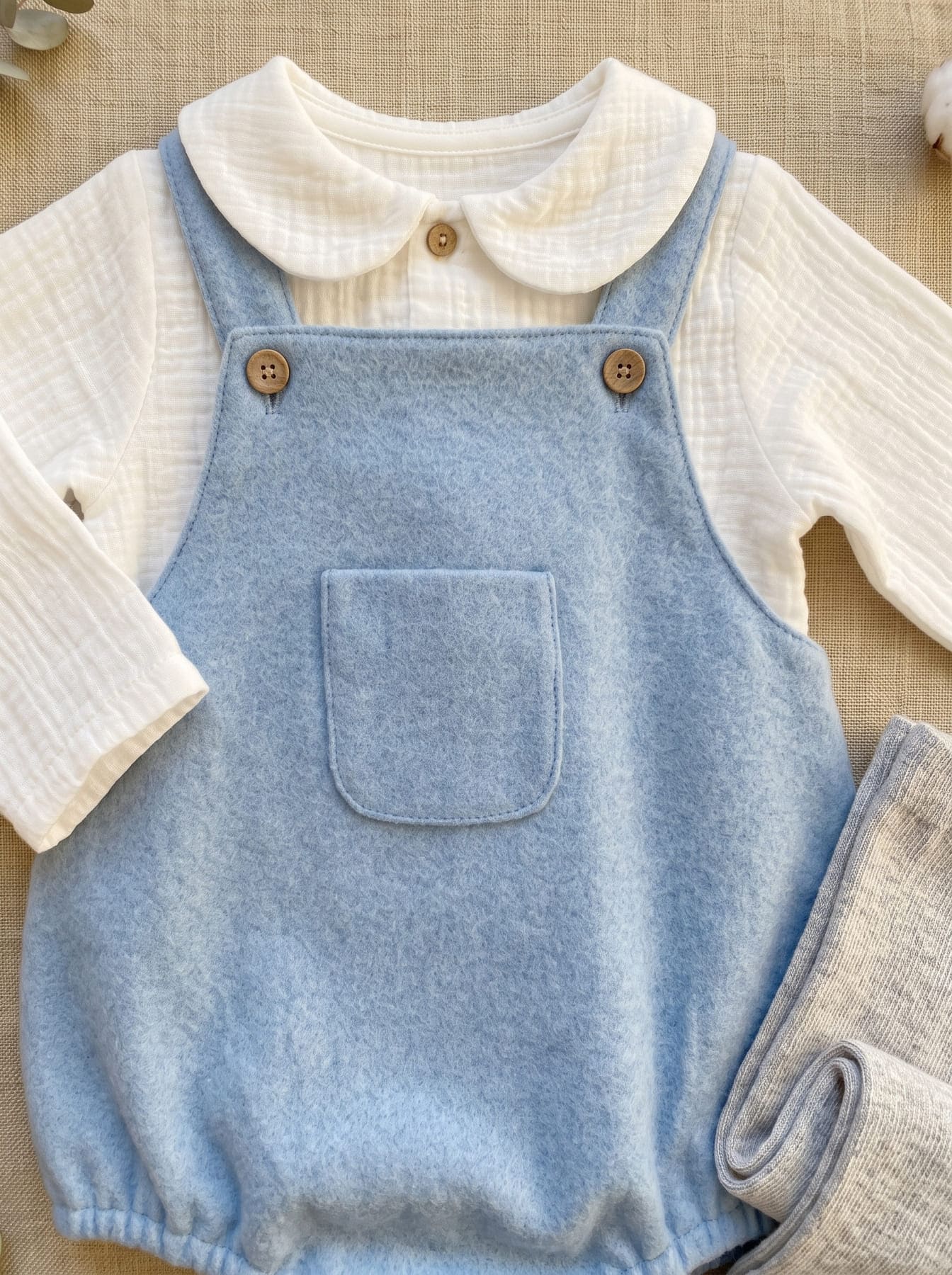 Detail of the sky blue baby outfit with romper and white top with round collar