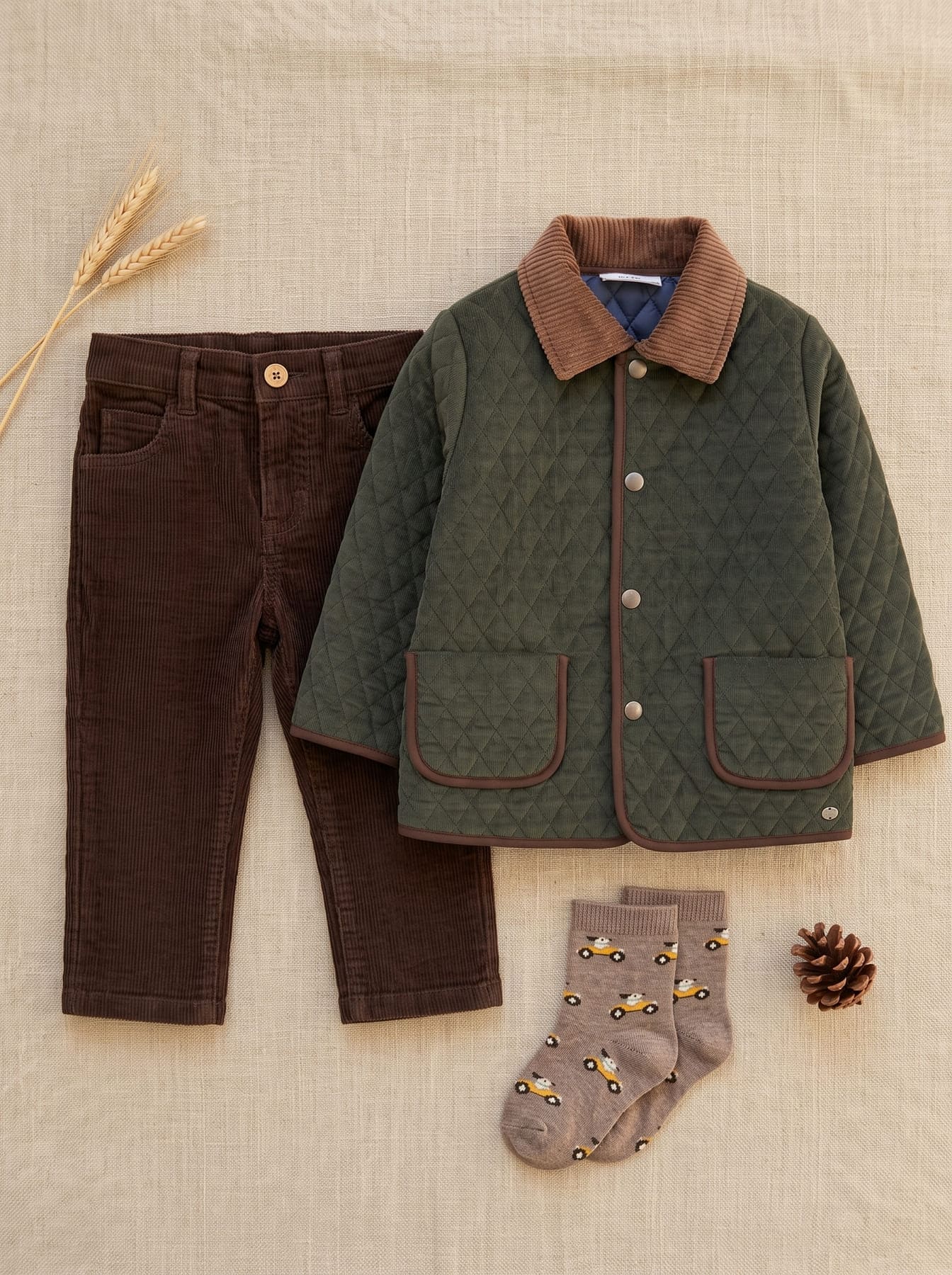 Tenue garçon avec veste matelassée vert foncé, pantalon marron et chaussettes à motifs