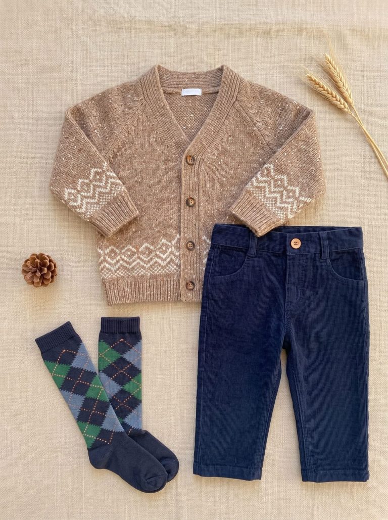 Look garçon avec cardigan beige à motifs, pantalon bleu marine et chaussettes à carreaux