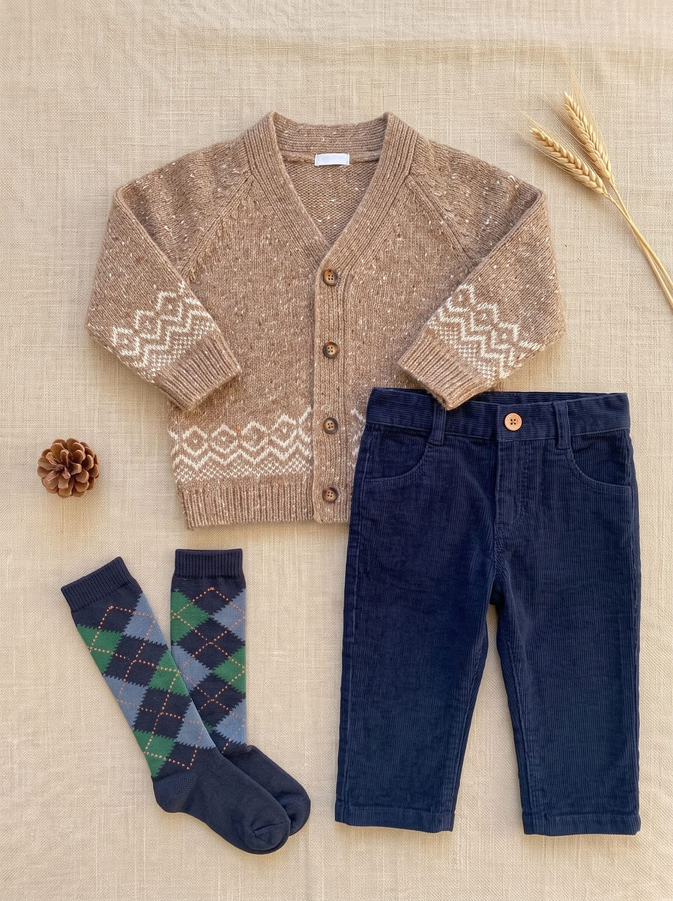 Look garçon avec cardigan beige à motifs, pantalon bleu marine et chaussettes à carreaux